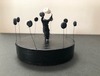 a sculpture of a man holding a ball on top of a black box