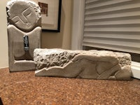two sculptures on a counter next to a window