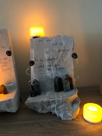 a set of candles on a table next to a piece of stone